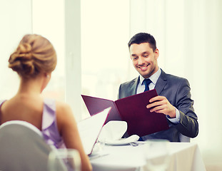 Image showing smiling young man looking at menu at restaurant