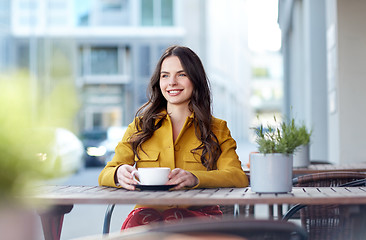 Image showing happy woman drinking cocoa at city street cafe