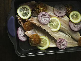 Image showing raw sea bass with lemon, onion and tomato ready