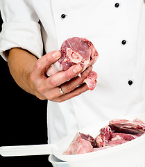 Image showing A professional chef in jacket, holding a lump of red meat