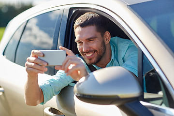 Image showing happy smiling man with smartphone driving in car