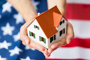 Image showing close up of hands holding house over american flag