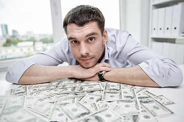 Image showing happy businessman with heap of money in office