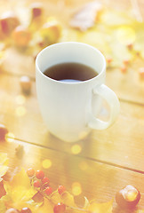 Image showing close up of tea cup on table with autumn leaves