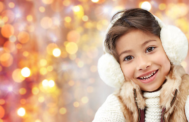 Image showing happy little girl in earmuffs over holidays lights