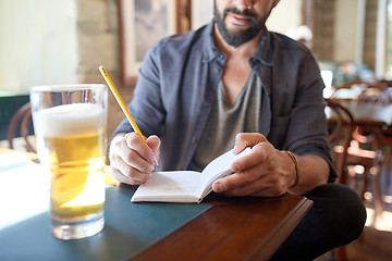 Image showing close up of man with beer and notebook at pub