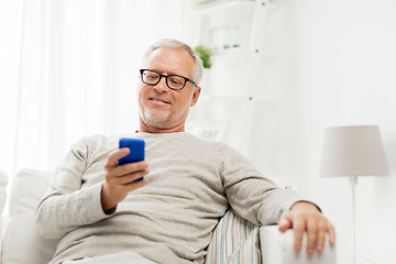 Image showing happy senior man texting on smartphone at home