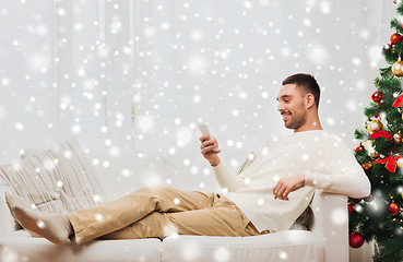 Image showing smiling man with smartphone at home for christmas