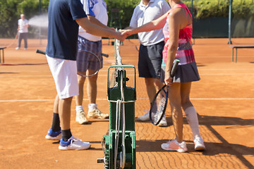 Image showing Mixed doubles tennis players shake hands before and after the te