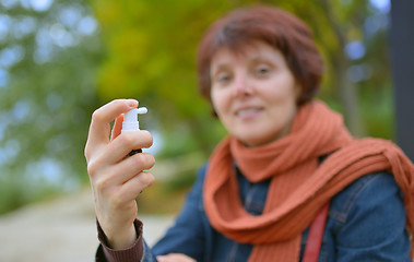 Image showing Young woman using throat spray 