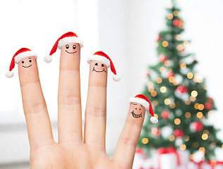 Image showing close up of hand with four fingers in santa hats