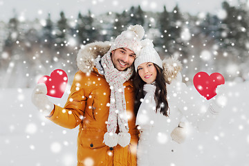 Image showing happy couple with red hearts over winter landscape