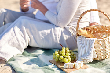 Image showing happy senior couple having picnic on summer beach