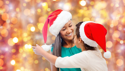 Image showing happy little girl in santa hat hugging her mother