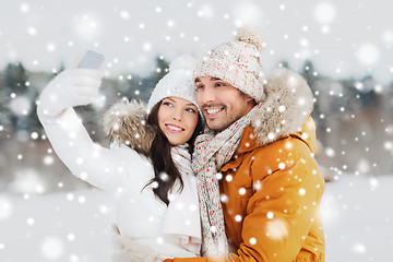 Image showing happy couple taking selfie by smartphone in winter