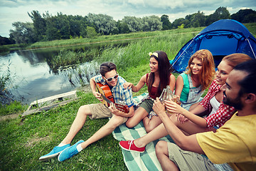 Image showing happy friends with drinks and guitar at camping