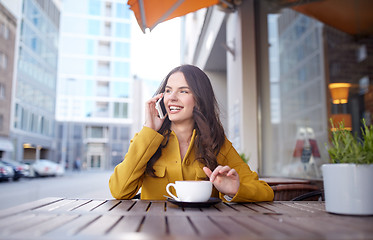 Image showing happy woman calling on smartphone at city cafe