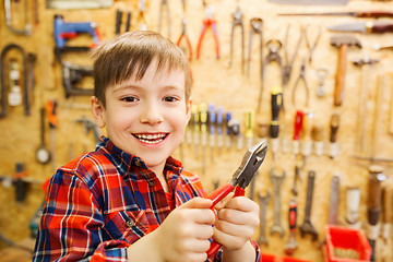 Image showing happy little boy with pliers at workshop