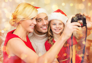 Image showing smiling family in santa helper hats taking picture