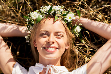 Image showing happy woman in wreath of flowers lying on straw