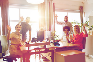 Image showing happy creative team waving hands in office