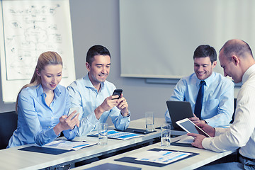 Image showing smiling business people with gadgets in office