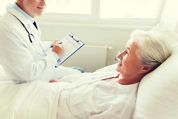 Image showing senior woman and doctor with clipboard at hospital