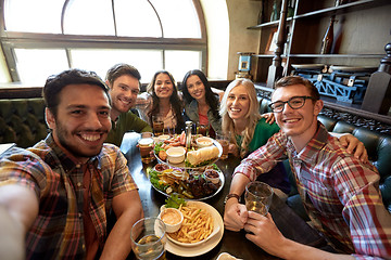 Image showing happy friends taking selfie at bar or pub