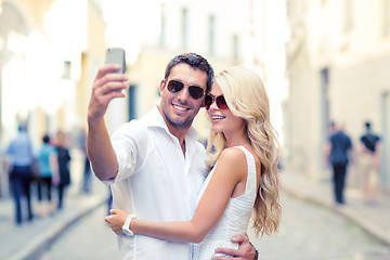 Image showing smiling couple with smartphone in the city