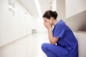 Image showing sad or crying female nurse at hospital corridor