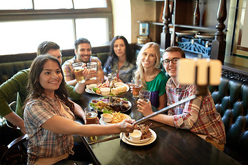 Image showing happy friends with selfie stick at bar or pub