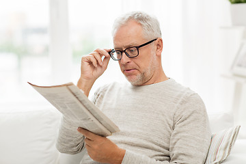 Image showing senior man in glasses reading newspaper at home