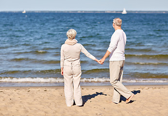 Image showing happy senior couple holding hands summer beach