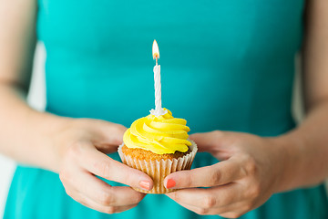 Image showing woman with burning candle on birthday cupcake