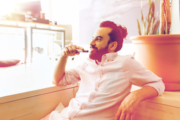 Image showing smiling man with beard and hair bun at office