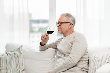 Image showing senior man drinking red wine from glass at home