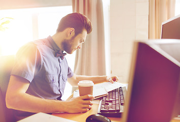 Image showing creative male worker drinking coffee and reading