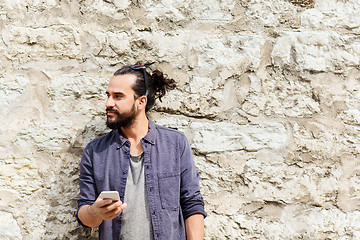 Image showing man with smartphone at stone wall