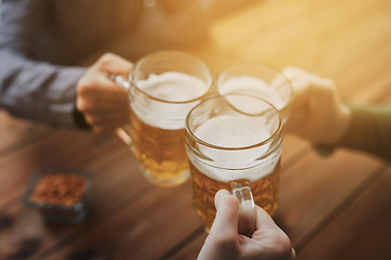 Image showing close up of hands with beer mugs at bar or pub