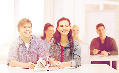 Image showing two teenagers with notebooks and book at school