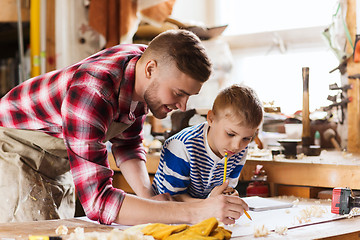 Image showing happy father and son with blueprint at workshop