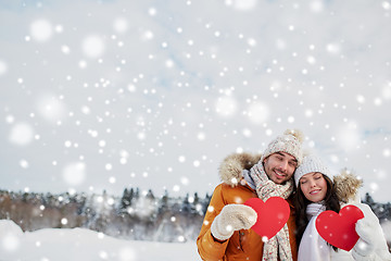 Image showing happy couple with red hearts over winter landscape