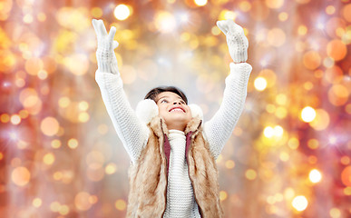 Image showing happy little girl in earmuffs over holidays lights