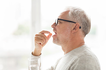 Image showing senior man taking medicine pill at home