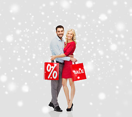 Image showing happy couple with red shopping bags over snow