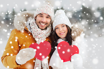 Image showing happy couple with red hearts over winter landscape