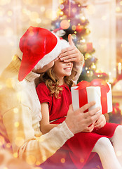 Image showing smiling father surprises daughter with gift box