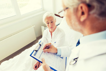 Image showing senior woman and doctor with clipboard at hospital