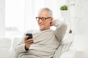 Image showing happy senior man texting on smartphone at home