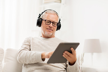 Image showing senior man with tablet pc and headphones at home